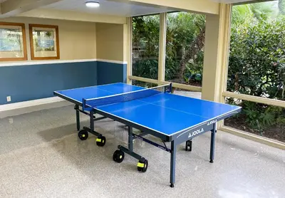 a blue ping pong table in a room with windows at Brooks Beach Vacations Cottage G5 Oceanside in Oceanside