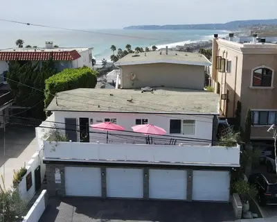 a white house with pink umbrellas on top of it at Spacious Ocean View Blufftop Compound in San Clemente
