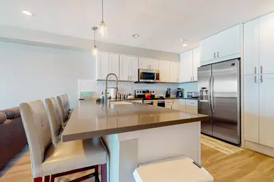 a kitchen with white cabinets and a stainless steel refrigerator at Blue Wave Penthouse in San Diego