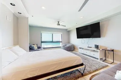 a bedroom with a large bed and a flat screen tv at Blue Wave Penthouse in San Diego