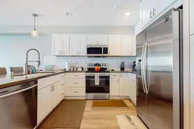 a kitchen with white cabinets and a stainless steel refrigerator at Blue Wave Penthouse in San Diego