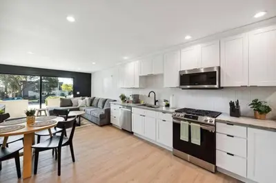 a kitchen with white cabinets and a table and a dining room at Coastal Living at its Finest Pacific Beach in San Diego