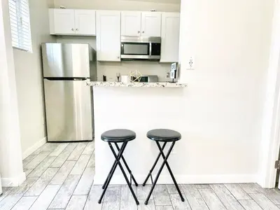 a kitchen with a stainless steel refrigerator and two stools at Modern Retreat Just Outside The City in San Diego