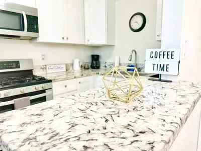 a kitchen with a marble counter top with a coffee time sign at Modern Retreat Just Outside The City in San Diego
