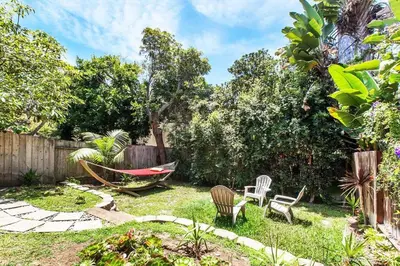 a backyard with a hammock and chairs and a fence at Coastal Paradise Blocks from Beacon's Beach in Encinitas