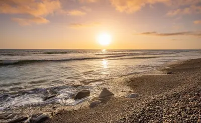 a sunset over the ocean with rocks on the beach at Ocean Dreamin in Encinitas