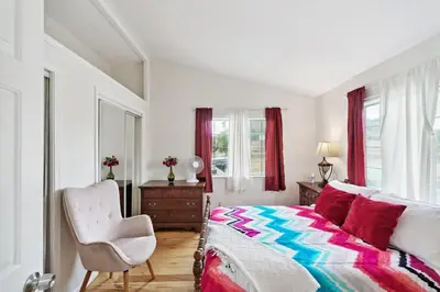 a bedroom with a bed and a chair and windows at Paradise On Earth residence in Lake Elsinore