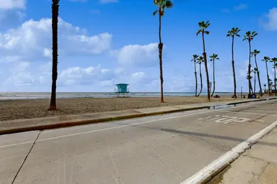 an empty street next to a beach with palm trees at Sandcastle Cottage 22 in Oceanside