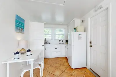 a kitchen with a white refrigerator and a table at Sandcastle Cottage 22 in Oceanside