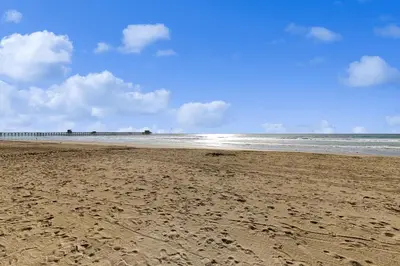a sandy beach with a pier in the distance at Sandcastle Cottage 22 in Oceanside