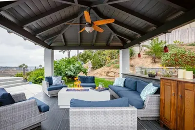 a patio with blue couches and a ceiling fan at Amazing Views with Heated Pool and Jacuzzi Near Beach in Solana Beach
