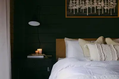 a bedroom with a green wall with a bed and candles at Award-Winning A-Frame with Views and Cedar Hot Tub in Julian