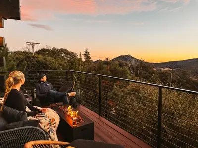 a man and woman sitting on a deck watching the sunset at Award-Winning A-Frame with Views and Cedar Hot Tub in Julian