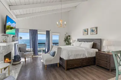 a bedroom with a large bed and a fireplace at Oceanfront 3-unit complex - Private Deck - BBQ in Oceanside