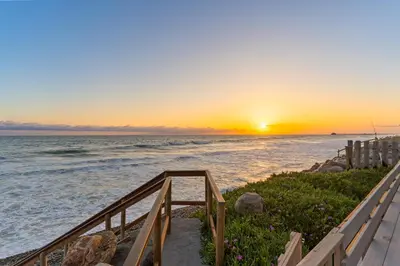 a stairway leading to the beach at sunset at 2BR Oceanfront Condo - Private Balcony - Spacious in Oceanside
