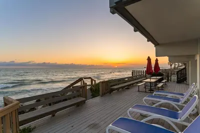 a deck with chairs and umbrellas and the ocean at Romantic Getaway - Luxury Oceanfront Studio - Private Balcony - Fireplace in Oceanside