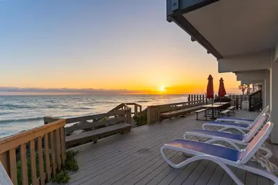a deck with chairs and umbrellas on the beach at Oceanfront Family Getaway - BBQ - Oceanfront Seating in Oceanside