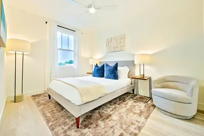 a white bedroom with a bed and a chair at Modern 4BR - Private Balcony - Garage Parking in Carlsbad