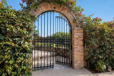 an entrance to a gate with a brick and iron fence at Rooftop Oceanview Patio - 5BR Remodeled Home in Carlsbad