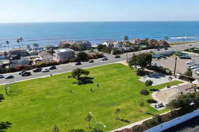 a park next to the ocean with people on the grass at Oceanview Rooftop Patio - Walk To The Beach & Park in Carlsbad