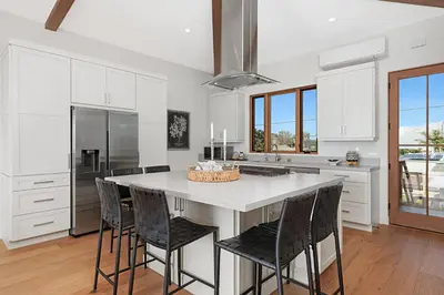 a kitchen with a large white island with black chairs at Oceanview Rooftop Patio - Walk To The Beach & Park in Carlsbad