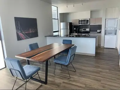 a kitchen with a wooden table and blue chairs at Modern 2-Bedroom Apartment in Little Italy in San Diego