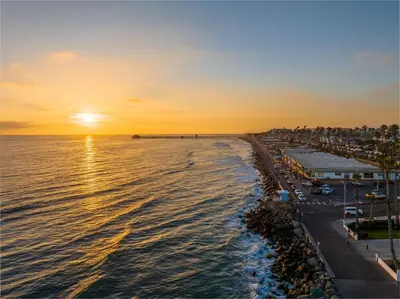a sunset over a beach with a city and the ocean at Oceanside Escape 700S-102 in Oceanside