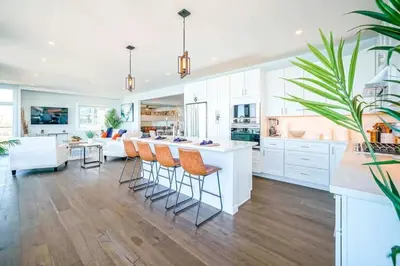 a kitchen with white cabinets and a large island with bar stools at Panoramic Ocean Vistas With Hot Tub and Firepit in San Diego