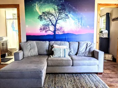 a couch in a living room with a tree mural at #2 - The Eagle's Perch in Pauma Valley