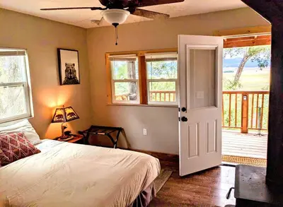 a bedroom with a bed and a door with a porch at #3 Howling Wolf's Lair - Cabin W/Fireplace & Views in Santa Ysabel