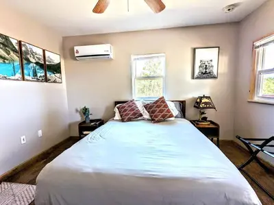 a bedroom with a large bed and two windows at #3 Howling Wolf's Lair - Cabin W/Fireplace & Views in Santa Ysabel