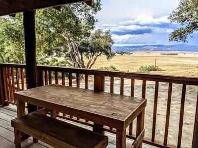 a wooden table on a porch with a view of a field at #7 Josie's Mountain Top Hideout-Cabin in the Woods in Santa Ysabel