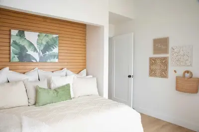 a bedroom with a white bed with a wooden headboard at Boho Solana Stunner in Solana Beach