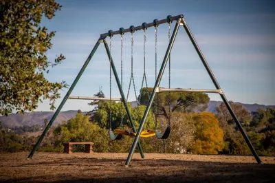 an empty swing set in a park with a bench at Nature lovers wellness home in Fallbrook