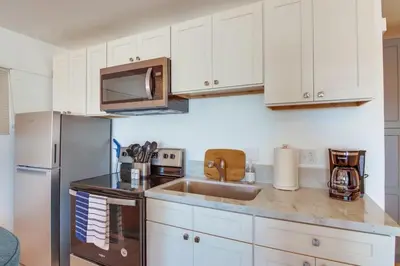 a kitchen with white cabinets and a stainless steel refrigerator at Bayside 1 in San Diego