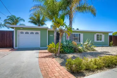 a green house with a palm tree in front of it at Nice home, Ocean views, and open space views. in Oceanside