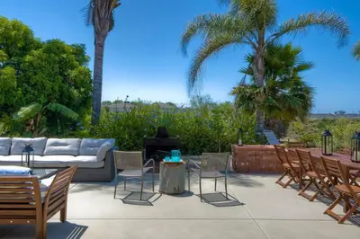 a patio with a couch and chairs and palm trees at Nice home, Ocean views, and open space views. in Oceanside