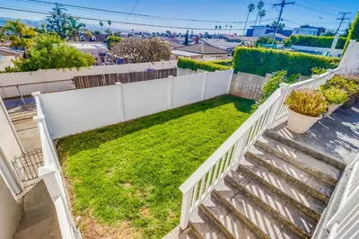a backyard with a white fence and grass at Point Loma Serenity in San Diego