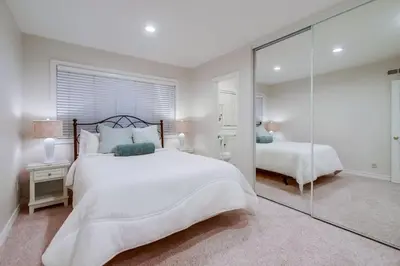 a white bedroom with a large bed and a mirror at Point Loma Serenity in San Diego