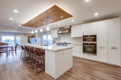 a kitchen with white cabinets and a large island with bar stools at Point Loma Serenity in San Diego