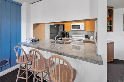 a kitchen with a counter with three bar stools at North Coast Village in Oceanside