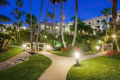 a pathway through a park with palm trees at night at North Coast Village in Oceanside
