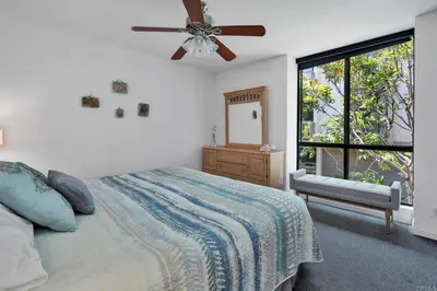 a bedroom with a bed with a ceiling fan and a window at North Coast Village in Oceanside