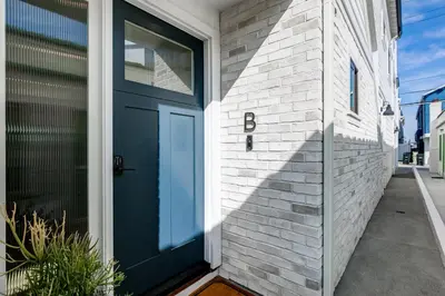 a blue door on a white brick house at BRAND NEW Luxury 1 Bedroom Condo Steps from the Beach in Newport Beach