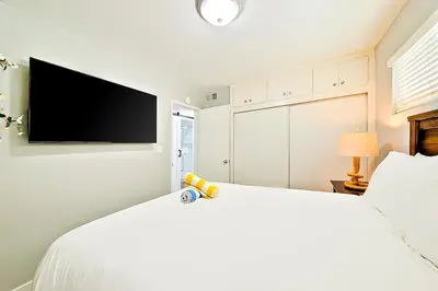 a bedroom with a white bed with a flat screen tv at Perfect 3 Bedroom Home between the Bay and Beach in Newport Beach