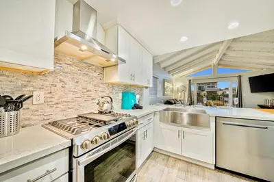 a kitchen with white cabinets and a stove top oven at 6 Bedroom Home with Rooftop Deck Between the Bay & the Beach in Newport Beach