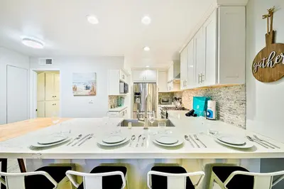 a large white kitchen with a large table and chairs at 2 Story Home with Rooftop Deck next to the Bay & Beach in Newport Beach