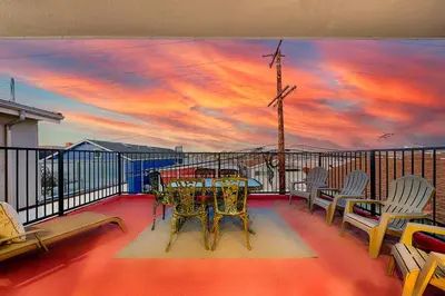 a table and chairs on a balcony with a sunset at 2 Story Home with Rooftop Deck next to the Bay & Beach in Newport Beach
