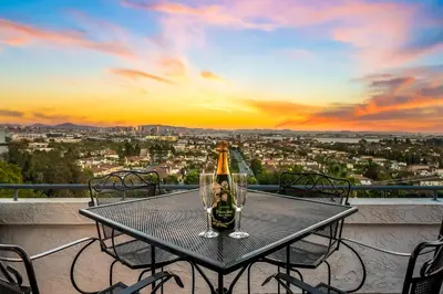 a table with a bottle of champagne on a balcony with a sunset at Spacious Beautiful Home with Stunning Bay Views in San Diego