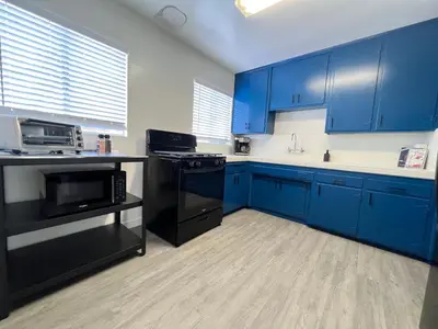 a blue kitchen with black appliances and blue cabinets at The Dugout in San Diego